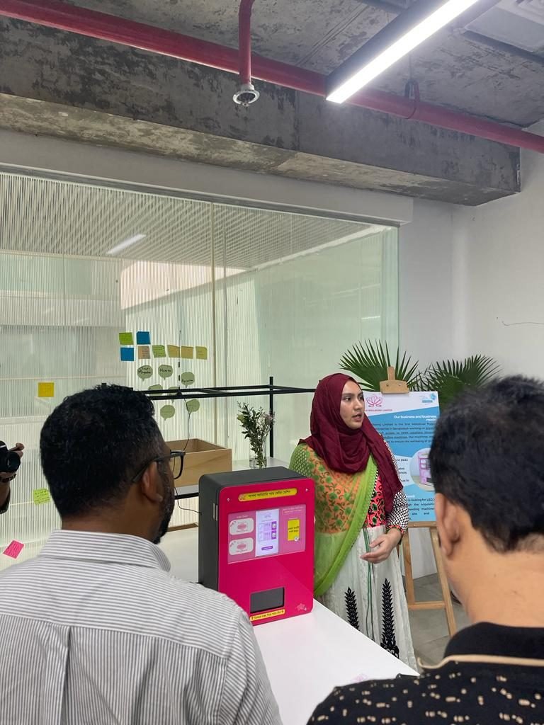 A Shapla Wellbeing team member presenting the vending machine and business model to partners